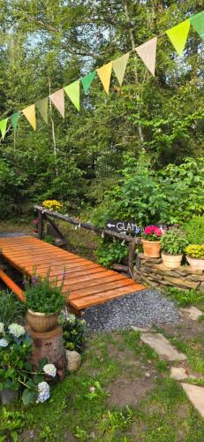 a wooden bridge in a garden with flags and flowers at Glamping Dedovles Vlastný stan in Vyšné Hágy