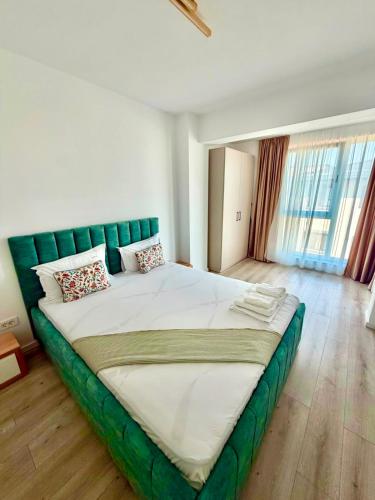 a large bed with a green headboard in a bedroom at DOCA Apartments 8 in Otopeni