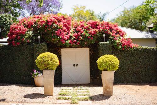a garden with pink flowers and a white door at Ambiance Guesthouse in Pretoria