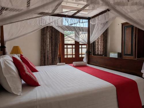 a bedroom with a large white bed with red pillows at Gangula Villa in Kandy