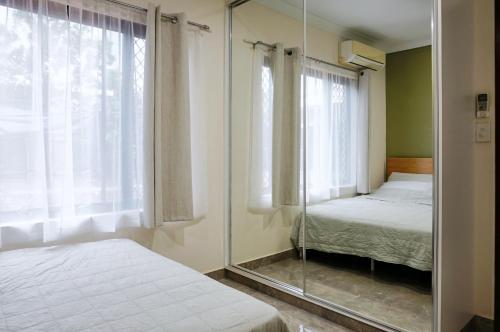 a mirror in a bedroom with a bed and a window at Emerald Oasis in Leanyer