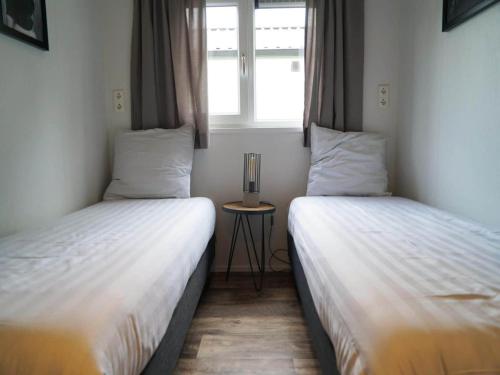 two twin beds in a room with a window at Chalet near Efteling Theme Park in Kaatsheuvel