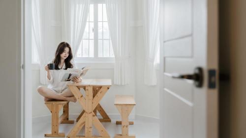 a woman sitting at a table reading a book at Taean Ocean Stay Pension in Taean