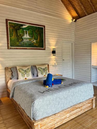 a bedroom with a large bed with a picture on the wall at Bali Dreams Bungalows in Tenganan