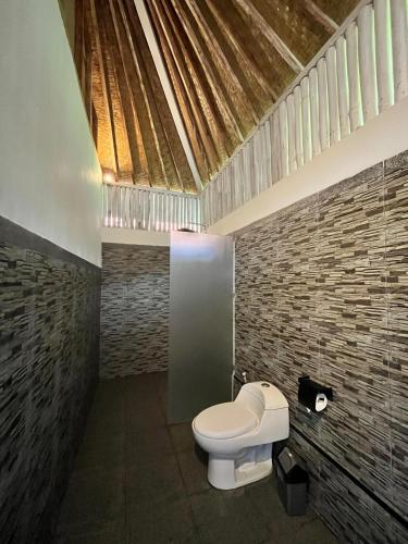 a bathroom with a toilet and a brick wall at Bali Dreams Bungalows in Tenganan