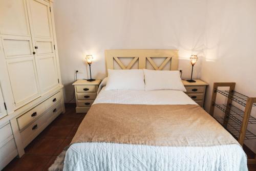 ein Schlafzimmer mit einem Bett, zwei Kommoden und zwei Lampen in der Unterkunft Apartamento Torre y Sol in Écija