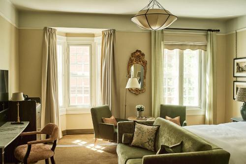 a bedroom with a bed and a couch and a table at Savoy 1918, a member of Small Luxury Hotels of The World in Oslo