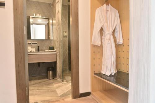 a white robe is hanging on a shelf in a bathroom at Paciano in Jalpāiguri