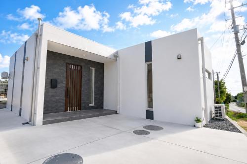 a house with white walls and a wooden door at Miyako Beach Resort in Hirara