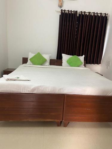 a bedroom with a large bed with green pillows at villas alleppey in Alleppey