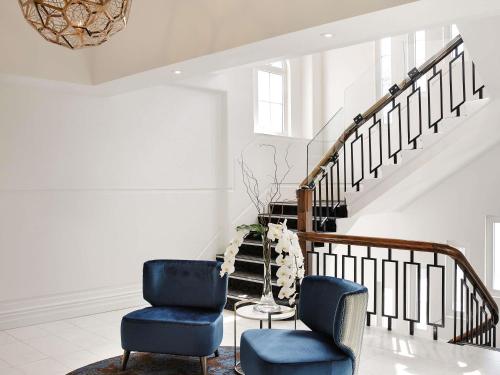 a living room with two chairs and a staircase at Fable Auckland, MGallery in Auckland