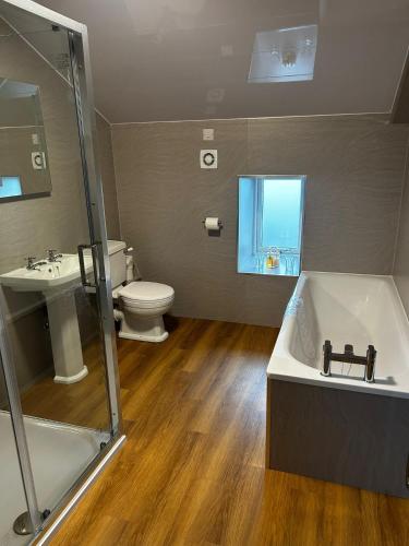 a bathroom with a tub and a toilet and a sink at Chevin End Guest House in Otley