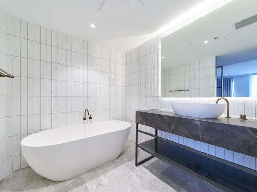 a white bathroom with a tub and a sink at Pullman Adelaide in Adelaide
