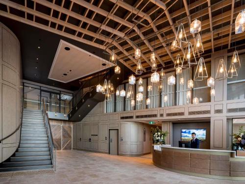 a lobby of a building with a staircase and chandeliers at The William Inglis Mgallery in Warwick Farm