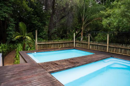 a swimming pool with a wooden deck and a swimming pool at Thamalakane River Lodge in Maun