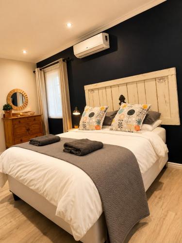 a bedroom with two beds and a air conditioner on the wall at Stay on Main - Studio Blue in Paarl