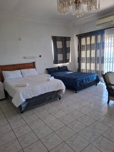 a bedroom with two beds and a chandelier at Nomty House in Durban