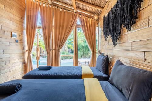 two beds in a room with a window at Mare Eco Bungalows - Kids & Family friendly in Kuta Lombok