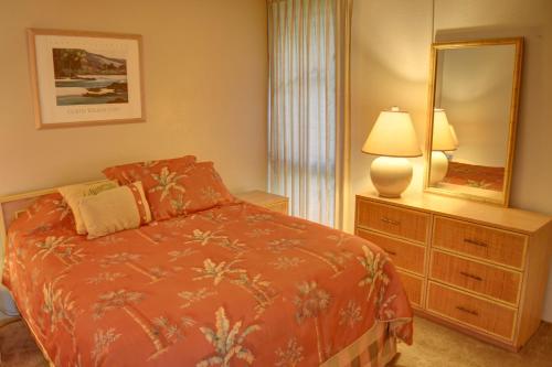 a bedroom with a bed and a mirror and a lamp at Maui Vista 3101 in Kihei