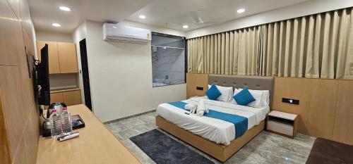 a bedroom with a large bed with blue pillows at Hotel Earth Orbit in Gandhinagar