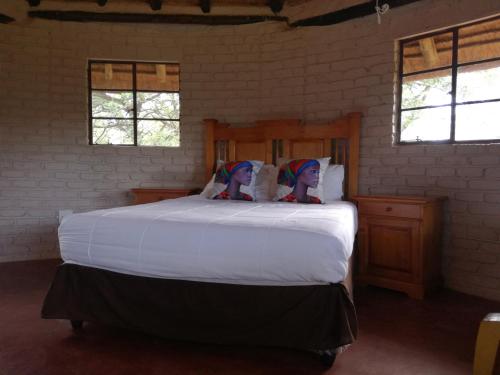 a bedroom with a large white bed with two dolls on it at Roundhouse Marloth Park in Marloth Park