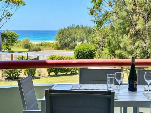 a table with a bottle of wine and glasses on a balcony at Fathoms 5 - 2BR beach resort apartment in Mollymook