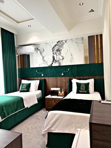 two beds in a hotel room with a green headboard at Qadim Hotel in Samarkand
