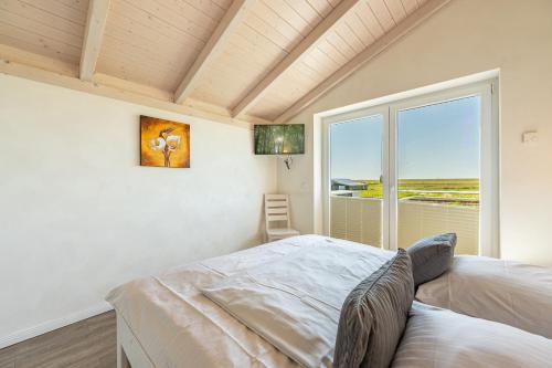 a bedroom with a bed and a large window at Ferienhaus Seestern in Dagebüll
