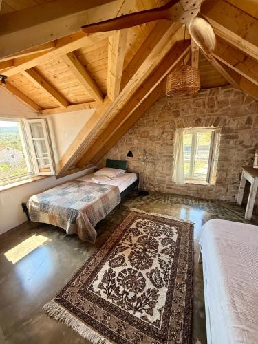 a attic bedroom with two beds and a rug at Mirca with seaview - charming stonehouse in Mirce