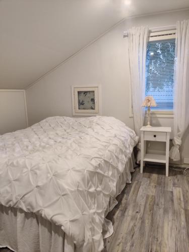 a bedroom with a white bed and a window at Omenapolun Onni in Taipalsaari