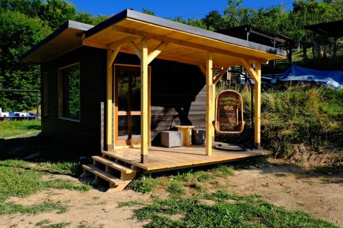 a small house with a wooden porch and a chair at Cabana din vale in Cioclovina