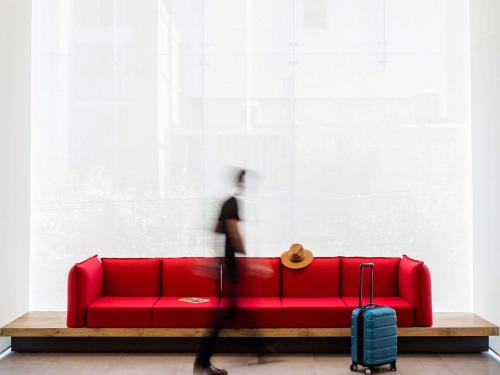 a person walking past a red couch with a suitcase at Ibis Mexico Tlalnepantla in Mexico City