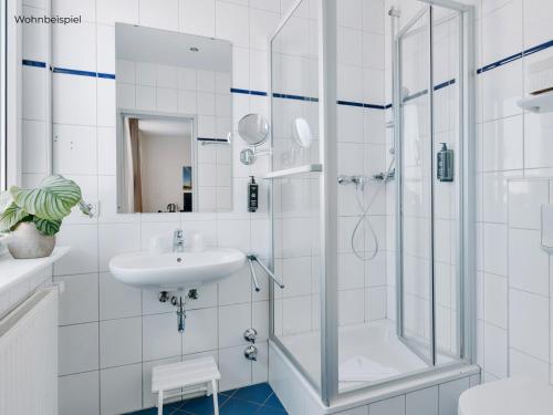 a white bathroom with a shower and a sink at Hotel Bloemfontein in Borkum