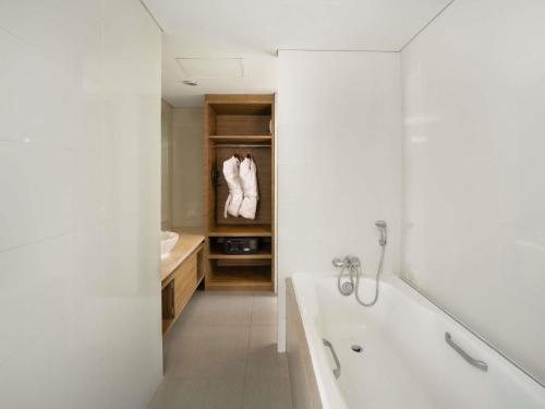 a white bathroom with a tub and a sink at Mercure Bandung Nexa Supratman in Bandung