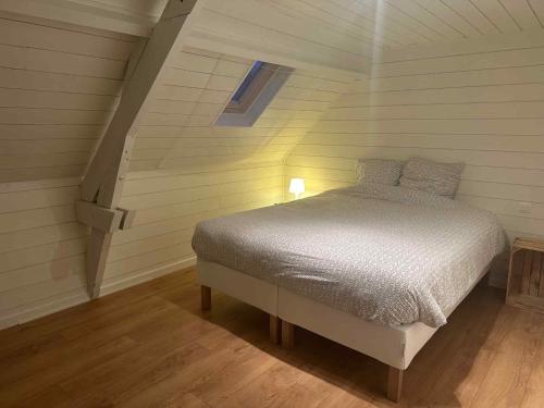 a small bedroom with a bed in a attic at Authentic rural square farm in Poperinge