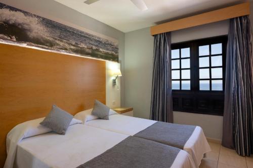 a hotel room with a bed and a window at Ona Las Rosas in Puerto de Santiago