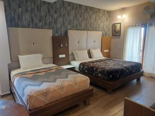 a bedroom with two beds and a window at Hotel Dreamland in Kodaikānāl