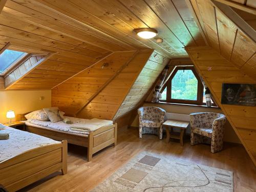 a attic room with a bed and two chairs at POD ROŻKAMI in Cisna