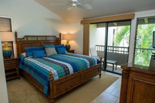 a bedroom with a bed with blue sheets and a window at Wailea Ekolu 1706 in Wailea