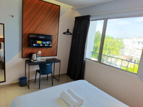 a bedroom with a bed and a desk and a window at Hotel 99 Kota Kemuning in Shah Alam