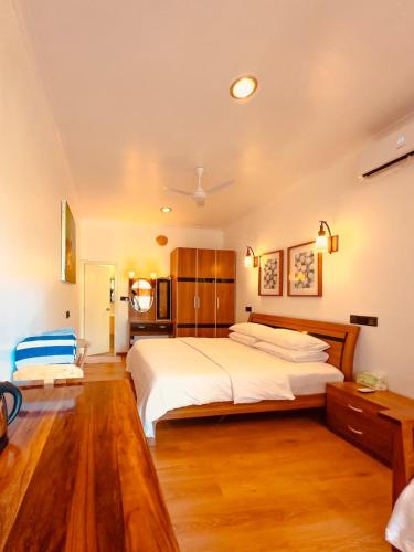 a bedroom with a large white bed and wooden floors at The Sultanate Courtyard Lh Hinnavaru 
