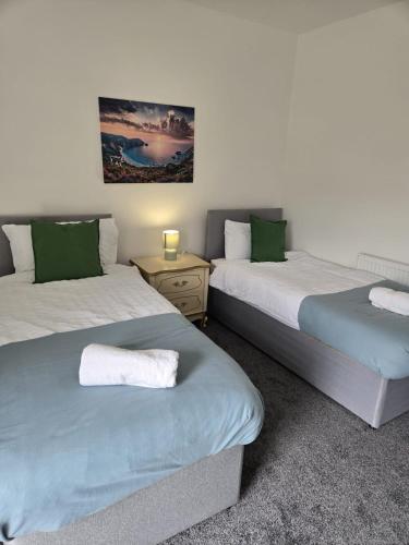 a bedroom with two beds with green pillows at Modern 3BDR Home l Sleeps 5 l Free Parking l Close to Train station and Shops in Worksop