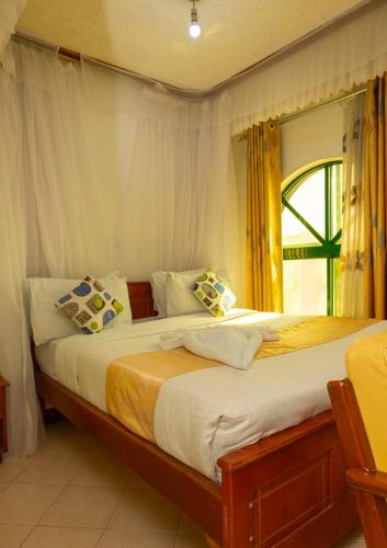 a bedroom with two beds with yellow curtains and a window at Comfy Inn Hotel in Eldoret