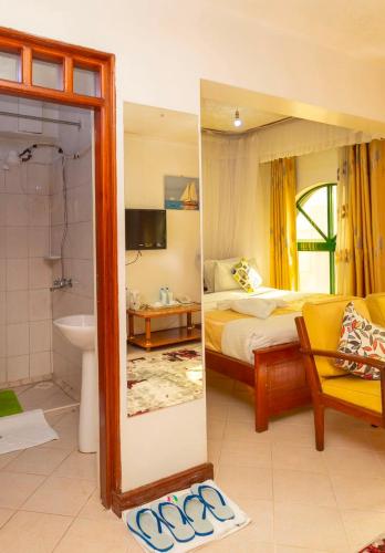 a bedroom with a bed and a bathroom with a mirror at Comfy Inn Hotel in Eldoret