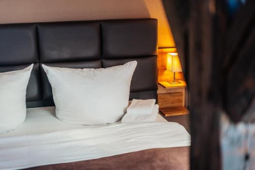 a bed with a black headboard and white pillows at Fichtenblick in Sankt Andreasberg