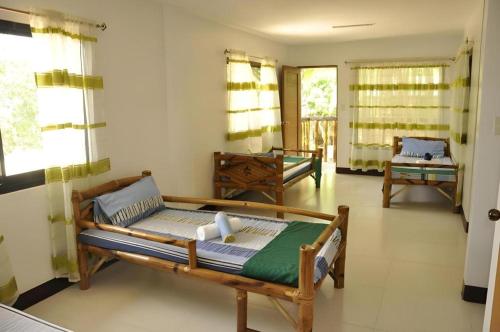 a living room with two beds and windows at Paseo Verde Beach Resort in Laiya