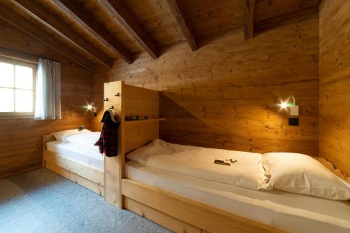 a bedroom with two beds in a wooden cabin at Chalet Selun - Luxury & Bergblick in Wildhaus