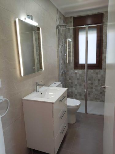 a bathroom with a sink and a toilet and a mirror at Apartamentos Turísticos El Collau in La Robellada de Onis