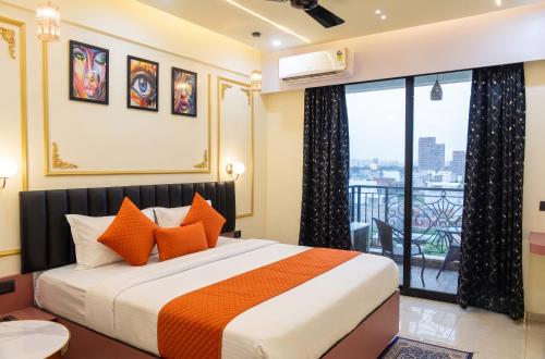 a bedroom with a bed with orange pillows and a balcony at Hotel Om Sai Villa Gomti Nagar, Lucknow in Lucknow