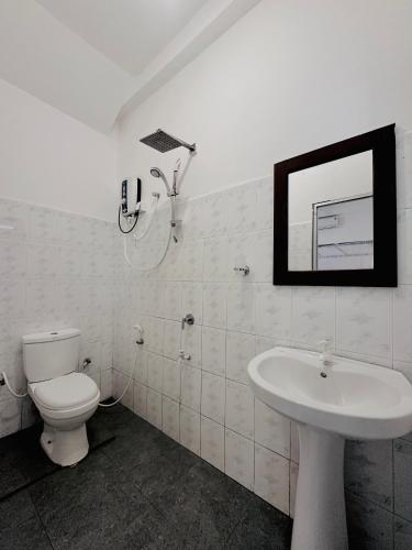 a bathroom with a toilet and a sink and a mirror at Rekawa Turtle Gate Hotel in Tangalle